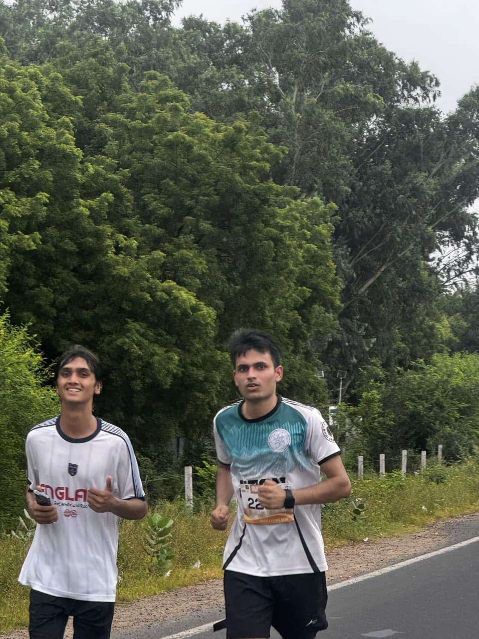 Two runners wearing race bibs moving together on the Ananta Run course.