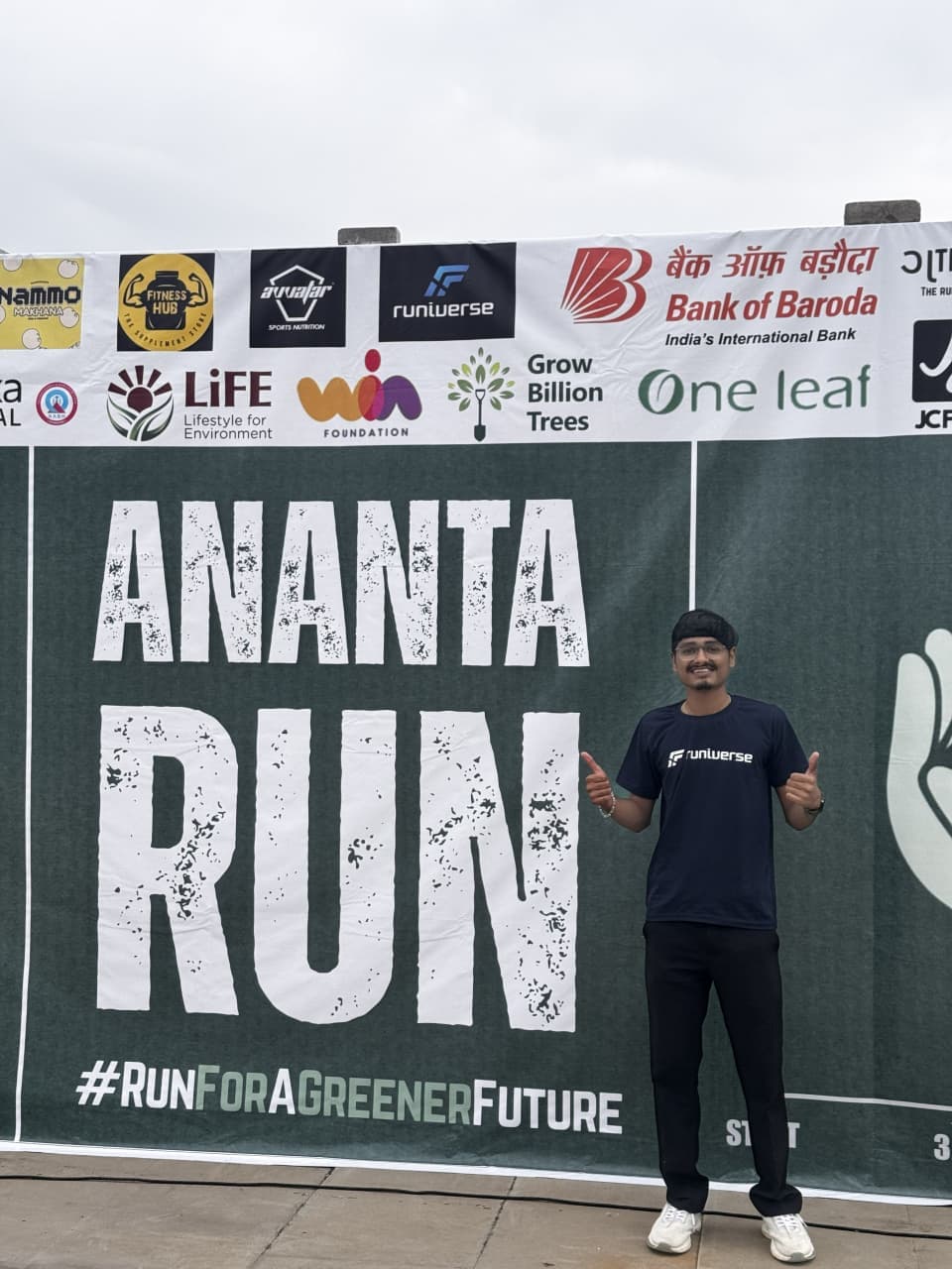 A Runiverse team member giving a thumbs-up in front of the Ananta Run banner.